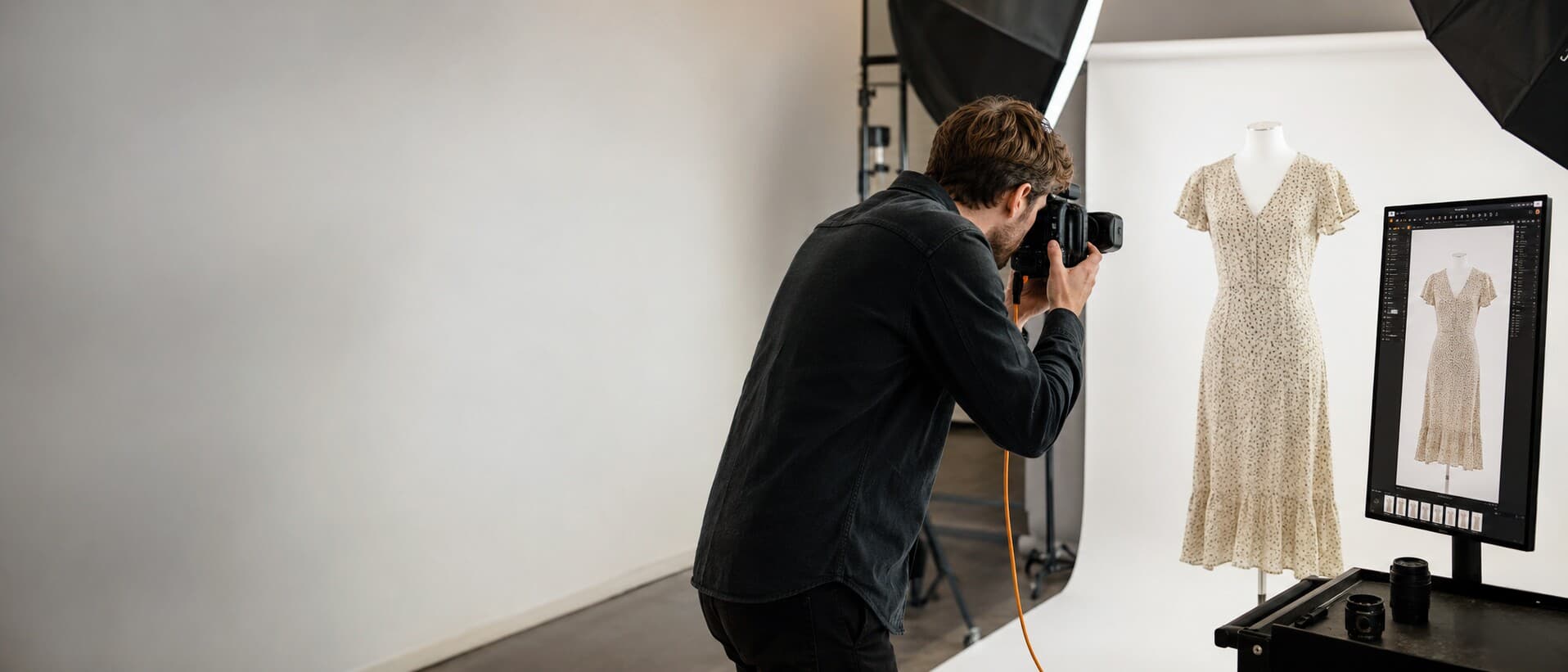Product photographer shooting a printed dress on a mannequin, tethered to a Capture One monitor, in the Pixol studio